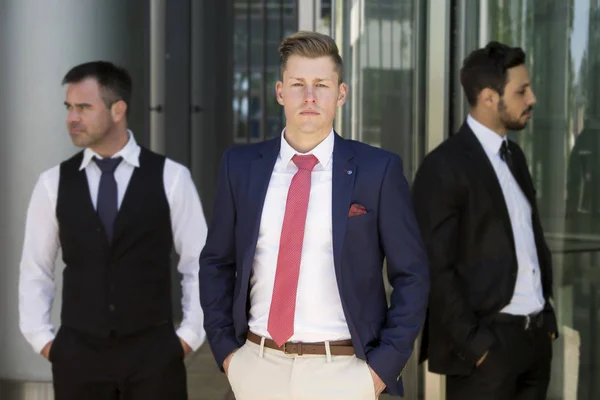 Три привлекательных молодых бизнесмена стоят снаружи — стоковое фото