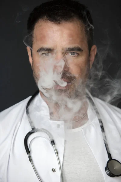 Bello medico fumare e soffiare fuori fumo — Foto Stock