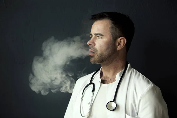 Bello medico fumare e soffiare fuori fumo — Foto Stock