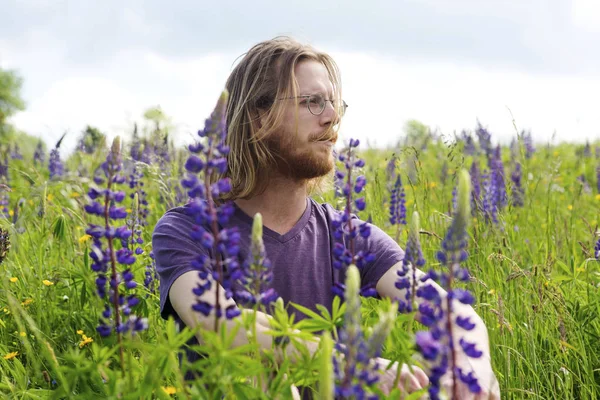 Çiçek alana oturan genç yakışıklı adam — Stok fotoğraf
