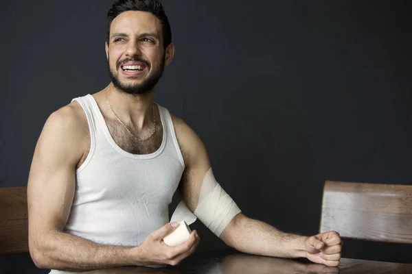 Porträt eines gutaussehenden Mannes, der sich einen Verband um den Arm legt — Stockfoto