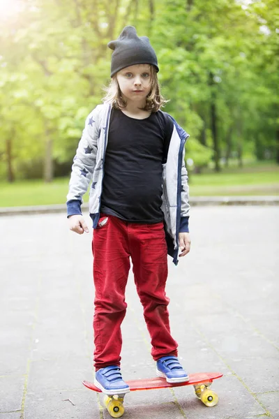 Blond boy standing outdoors on skateboard — Stock Photo, Image