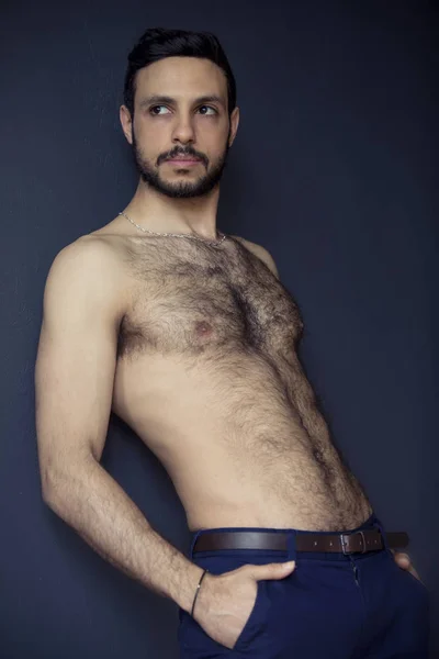 Hombre peludo sin camisa apoyado contra la pared — Foto de Stock