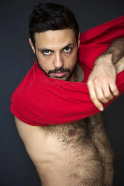 Handsome hairy man taking off his t-shirt — Stock Photo, Image