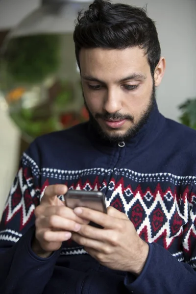 Bonito homem de cabelos escuros olhando para o seu telefone — Fotografia de Stock