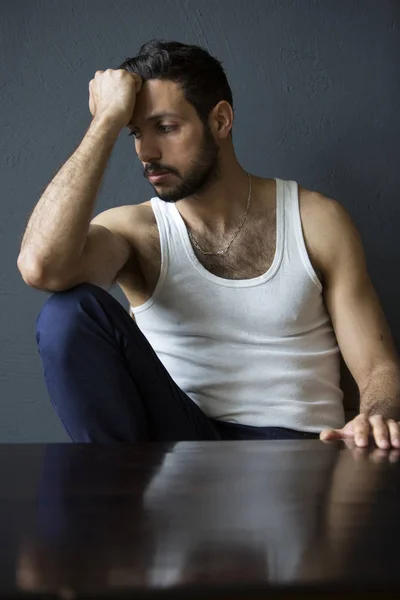 Porträt eines gutaussehenden dunkelhaarigen Mannes, der am Tisch sitzt — Stockfoto