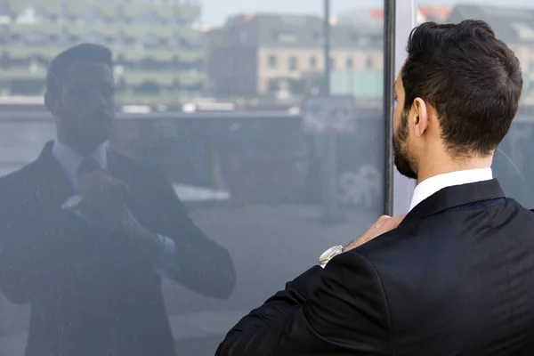 Бизнесмен стоит снаружи и смотрит на свою жизнь в зеркале. — стоковое фото