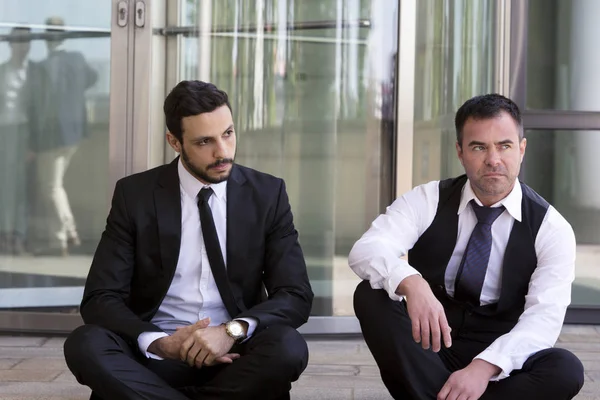 Dos hombres de negocios sentados fuera y mirando en serio —  Fotos de Stock