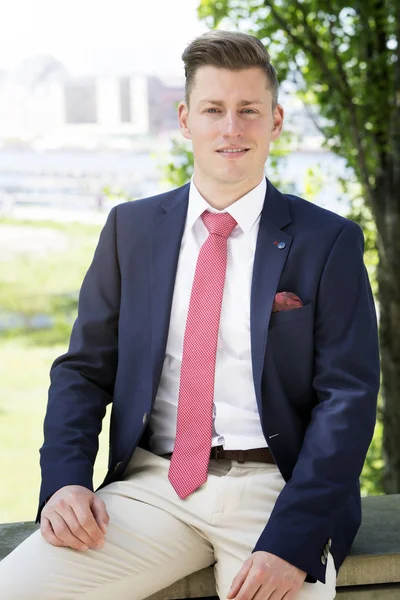 Businessman sitting outside and smiling at camera — Stock Photo, Image