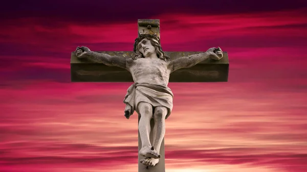 Sten kors med Jesus och röd himmel — Stockfoto