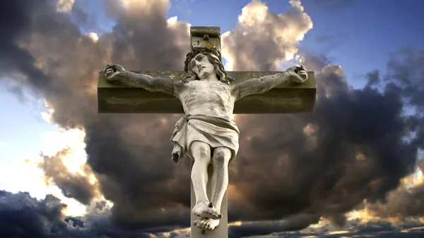 Stone cross with Jesus and cloudy sky — Stock Photo, Image