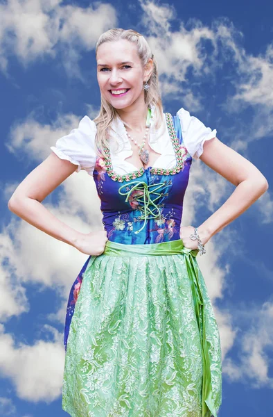 Sorridente donna bionda in dirndl davanti al cielo blu — Foto Stock