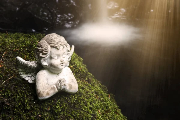 Praying stone angel on moss in front of waterfall — Stock Photo, Image