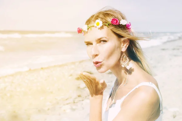 Blond woman on the beach blowing a kiss — Stock Photo, Image