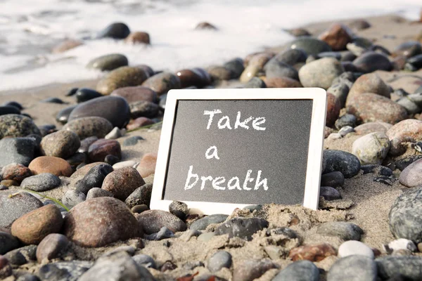Quadro negro deitado na praia com as palavras "Respire um pouco" — Fotografia de Stock