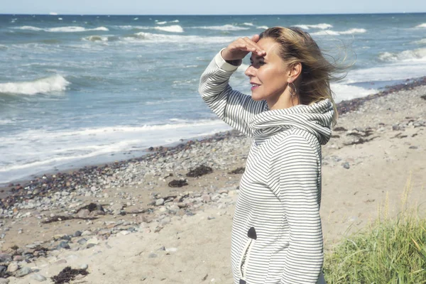Mujer de pie en la playa y mirando a la distancia — Foto de Stock