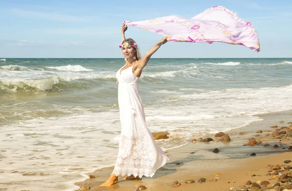 Mujer caminando en la playa y sosteniendo chal en el viento — Foto de Stock