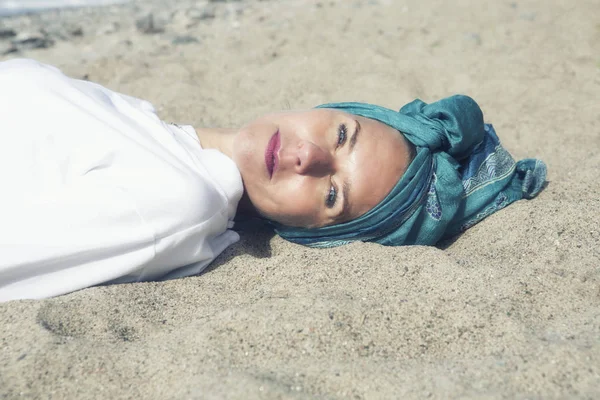 Mujer acostada en la playa y sonriendo a la cámara — Foto de Stock