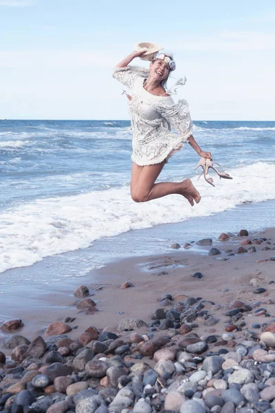 Mujer rubia en vestido blanco saltando en la playa — Foto de Stock