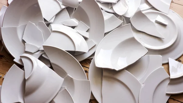 Weiße zerbrochene Teller auf einem Holzboden — Stockfoto