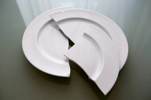 Λευκό σπασμένο πιάτο στο γυάλινο τραπέζι — Φωτογραφία Αρχείου