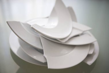 broken white plates on glass table clipart