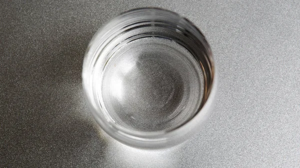 Glass of water on silver plate Royalty Free Stock Images