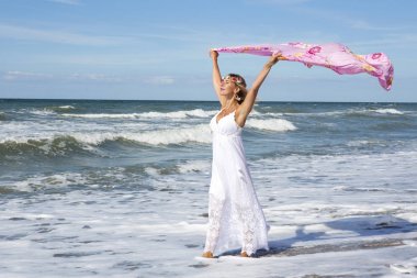 Sahilde yürüyüş ve bir şal rüzgarda tutan kadın