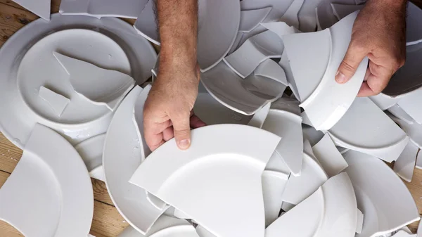 Manos recogiendo platos blancos rotos de piso — Foto de Stock