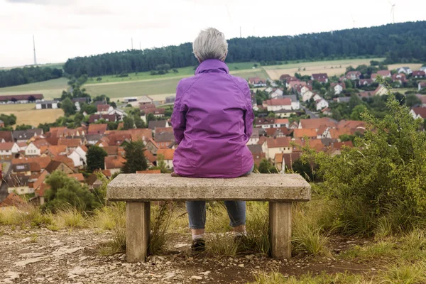 Bankta oturan ve kasaba yaşlı kadın — Stok fotoğraf