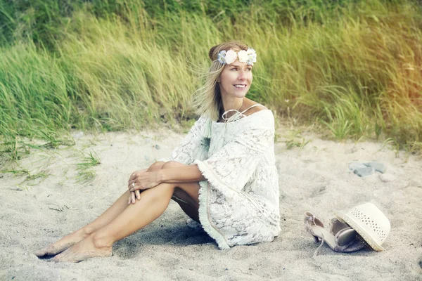 Mujer rubia en vestido blanco sentada en la playa — Foto de Stock
