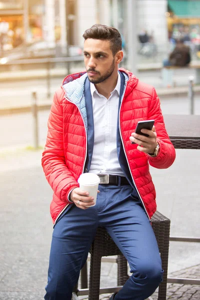 Bonito homem sentado fora segurando um telefone — Fotografia de Stock