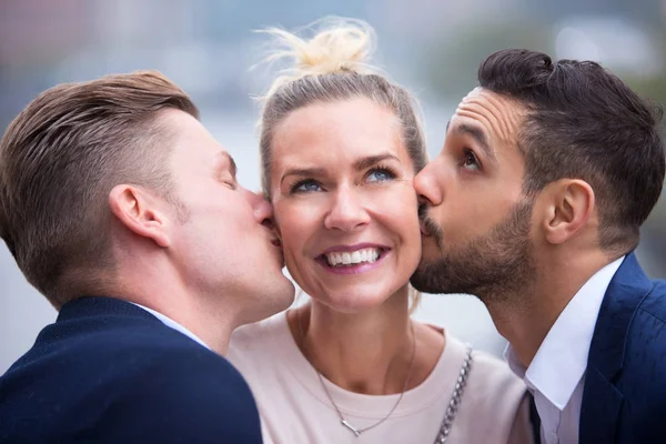 Deux jeunes hommes embrassant femme sur ses joues — Photo