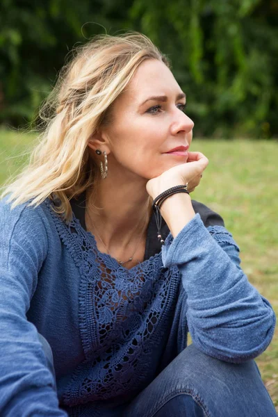 Blond kvinna sitter utanför i parken — Stockfoto