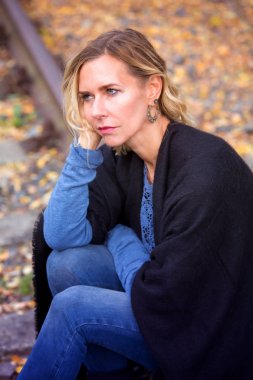 iz parça üzerinde oturan ve üzülmüş sarışın kadın