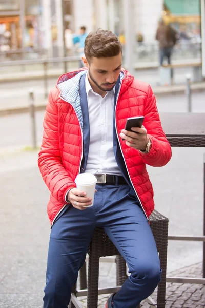 Bonito homem sentado fora segurando um telefone — Fotografia de Stock