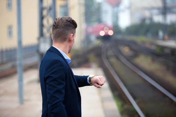Mann kontrolliert die Uhrzeit und wartet auf Zug — Stockfoto