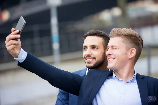 Två stilig affärsmän talar en selfie — Stockfoto
