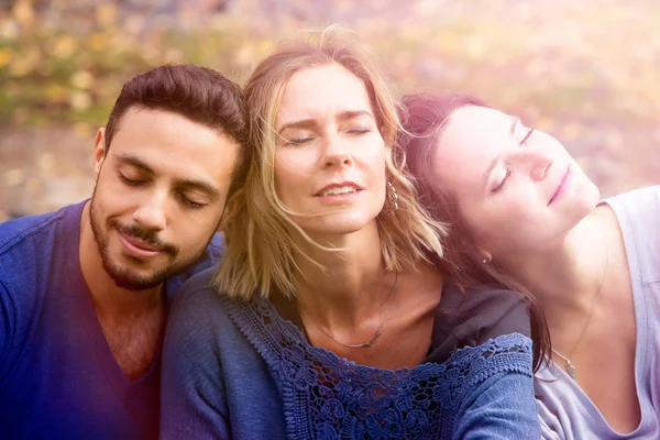 Portrait of three friends sitting outside in the sun — Stock Photo, Image