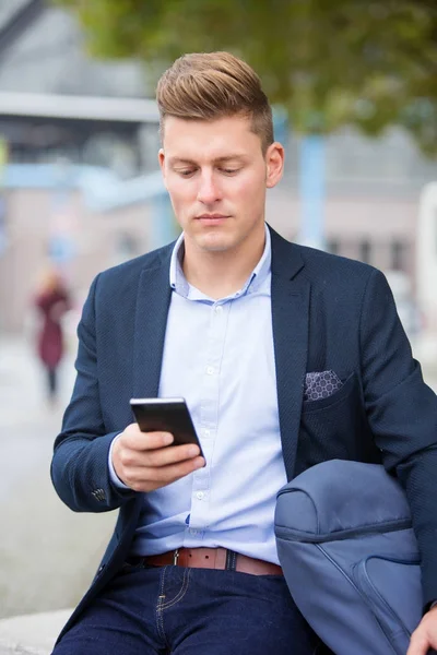 Stilig affärsman sitter utanför med sin telefon — Stockfoto