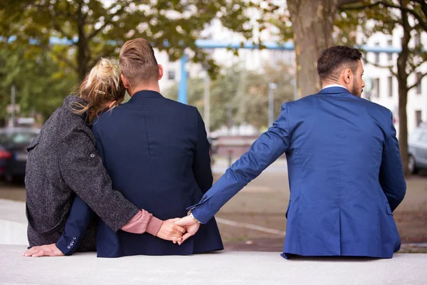 Coppia abbracciare mentre la donna si tiene per mano con un altro uomo — Foto Stock