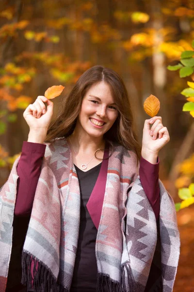 Jovem morena mulher na floresta segurando folhas — Fotografia de Stock