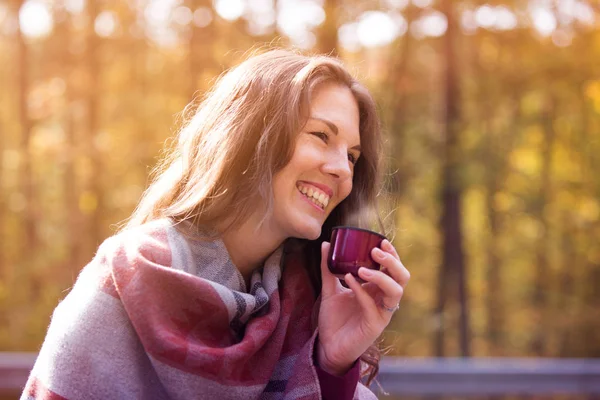 Mujer joven afuera bebiendo de la taza en otoño — Foto de Stock