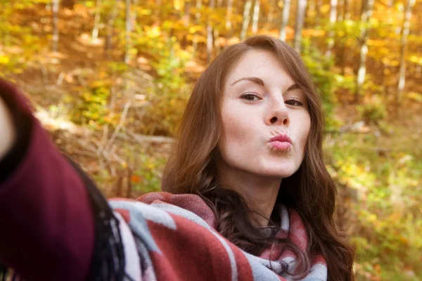 Jovem mulher fora no outono e tomar uma selfie — Fotografia de Stock