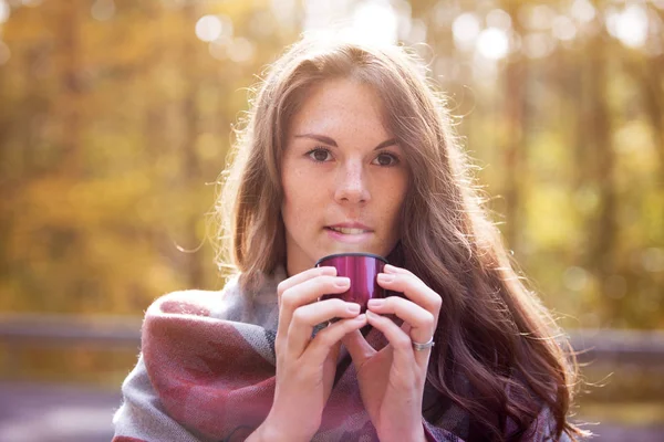 Mujer joven afuera bebiendo de la taza en otoño — Foto de Stock