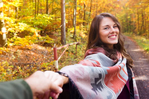 Jeune femme tenant la main de l'homme et marchant dans la forêt en automne — Photo