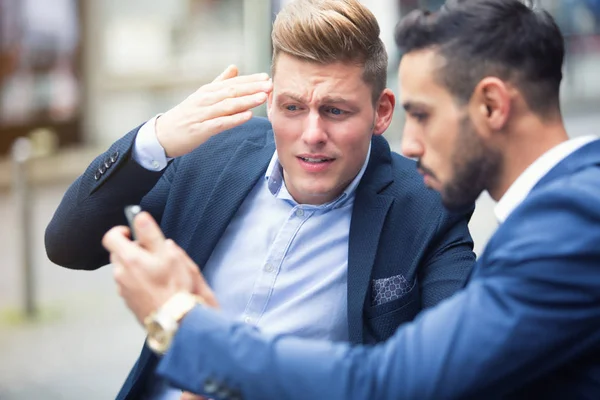 Dois homens de negócios de pé fora e olhando para o telefone — Fotografia de Stock