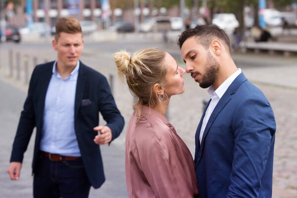 woman kissing man while another is upset
