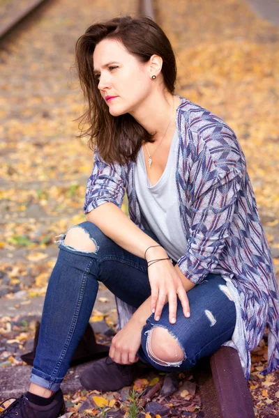 Portrait of beautiful woman sitting on train tracks — Stock Photo, Image