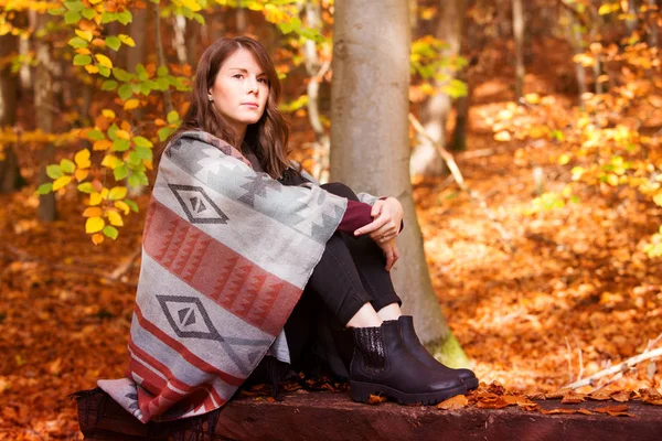 Mujer joven sentada en el bosque en otoño y mirando triste —  Fotos de Stock
